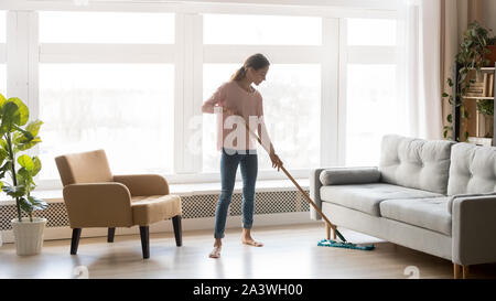 Giovane donna casalinga pavimento pulito nel soggiorno moderno Foto Stock