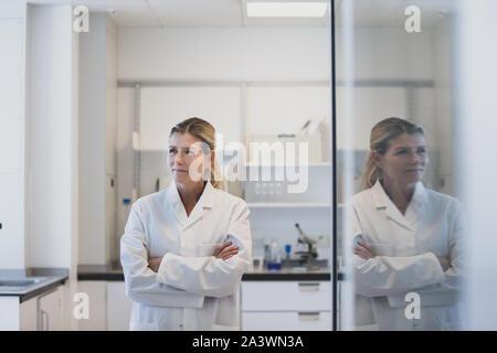 Donna scienziato guardando fuori della finestra con la riflessione Foto Stock