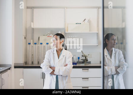 Donna scienziato guardando fuori della finestra con la riflessione Foto Stock