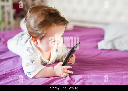 Il bambino apprende dal telefono cellulare. Piccolo Neonato per raggiungere un telefono mobile Foto Stock