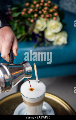 Cameriera una colata di latte fresco il caffè in un bar Foto Stock