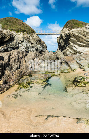 La passerella che collega la terraferma a Porth Island a Porth Beach in Newquay in Cornovaglia. Foto Stock