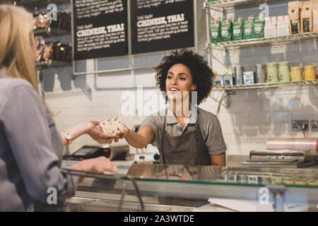 Assistente vendite di servire il cliente a un contatore di deli Foto Stock