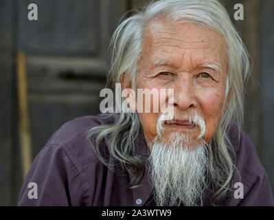 Anziani Sino-Burmese uomo con lunghi capelli grigi e un tradizionale cinese lunga barba pone per la fotocamera. Foto Stock