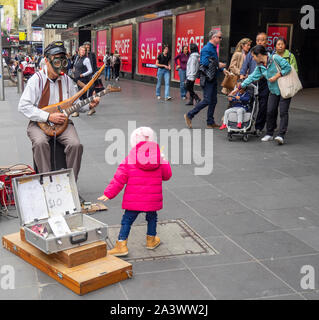 Suonatore ambulante di sesso maschile che indossa una maschera a gas suonando una chitarra elettrica in Bourke St Mall Melbourne Victoria Australia. Foto Stock