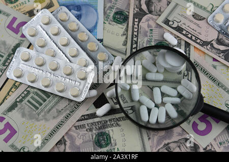 Magnifier, compresse e termometro su sfondo di diversi paesi moneta note. Il concetto di disponibilità di medico e di medico crescente exp Foto Stock