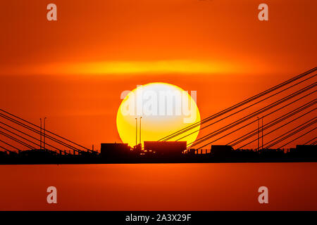 Tramonto sul cavo alloggiato a ponte con silhouette di automobile attraversando la baia mare Foto Stock