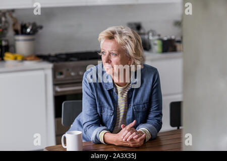Adulto donna guardando fuori della finestra con una tazza di tè Foto Stock