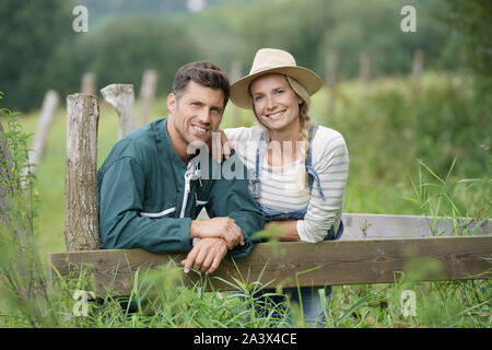 Ritratto di Coppia sorridente di agricoltore in piedi da recinzione Foto Stock