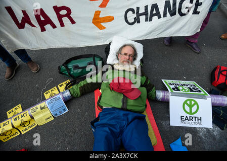 Londra, Regno Unito. Il 10 ottobre 2019. Titolare di pensione o di rendita attivista Brian Larkin, bracci fissati a tubo di plastica, giace sul terreno in Trafalgar Square durante il giorno 4 di estinzione Rebellion cambiamenti climatici protesta nella capitale. Gli attivisti chiedono al governo di prendere provvedimenti immediati contro le conseguenze negative del cambiamento climatico. Credito: Stephen Chung / Alamy Live News Foto Stock