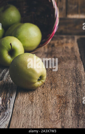 Close-up di fresche e mature mele verdi nel cesto in vimini su tavola in legno rustico a casa, impianti alimentari a base di Foto Stock