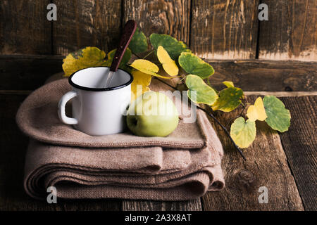 Vuoto rurale bianco mug, mela verde e sciarpa di lana, autunno tea time, casa accogliente Foto Stock