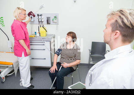 Femmina infermiera registrata la misura della pressione del sangue di una donna anziana in un ospedale Foto Stock