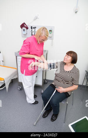 Femmina infermiera registrata la misura della pressione del sangue di una donna anziana in un ospedale Foto Stock