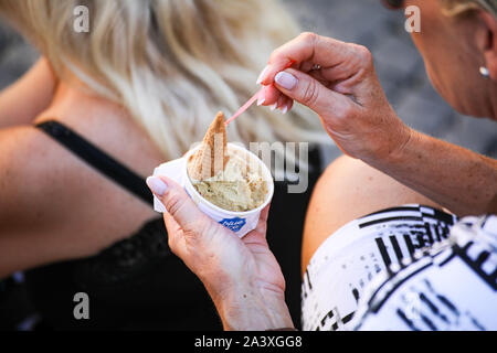 Donna di mezza età mangiare il gelato in Roma, Italia Foto Stock