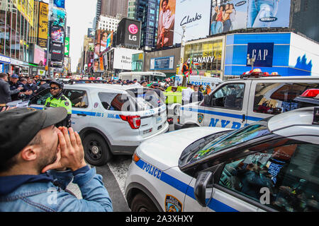 New York, Stati Uniti d'America. 10 ottobre, 2019. La polizia si riuniranno presso la caviglia di una piccola barca a vela che è stato sospeso in Times Square come parte di una protesta da parte del gruppo ambientalista estinzione della ribellione del 10 ottobre 2019 nella città di New York. Come turisti e Newyorkesi guardare, le vittime sono stati arrestati mentre i manifestanti di escalation di modifica bloccati o vittime della tratta di esseri umani in midtown Manhattan. Il gruppo sta protestando il cambiamento climatico durante tutta la settimana in tutta la città di New York e in diversi altri luoghi in tutto il mondo. Credito: Brasile Photo Press/Alamy Live News Foto Stock