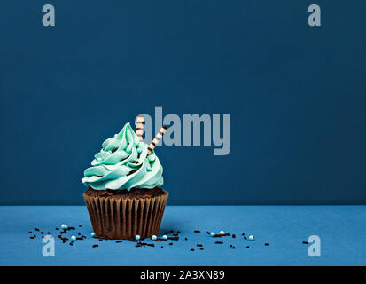 Blu Tortina di compleanno con cioccolato spruzza contro uno sfondo blu. Foto Stock