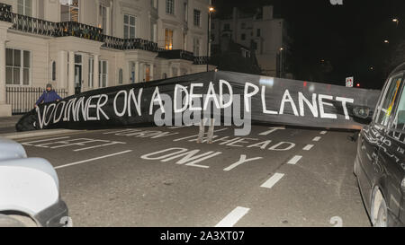Londra, UK, 10 ott 2019. I manifestanti bloccano la strada all'esterno dell'hotel con un 'No la cena su un pianeta morto' banner, riferendosi alla cena annuale manifestazione all'interno. Estinzione della ribellione manifestanti da Londra XR gruppi, comprese le XR batteristi, protesta al di fuori della British Plastics Federation (BPF) cena annuale presso il Royal Lancaster Hotel questa sera. L'evento è un'industria annuale e l'evento di networking per il settore della plastica. Molti dei partecipanti di interagire e chattare con i manifestanti in questa occasione. Credito: Imageplotter/Alamy Live News Foto Stock