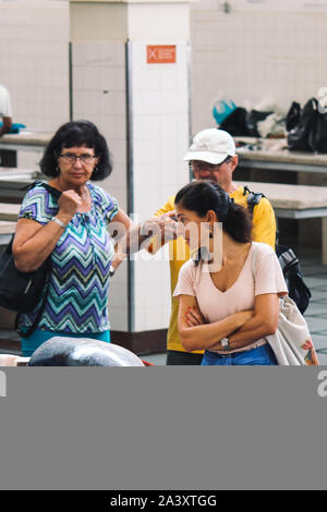 Funchal, Madeira, Portogallo - Sep 21, 2019: Donna fresco di acquisto tonno crudo pesce da un venditore di un tradizionale mercato del pesce Mercado dos Lavradores. Enti locali il mercato coperto. L'abuso di animali, diritti, crudeltà. Foto Stock