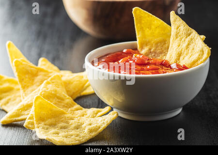 Il mais nacho chips e pomodoro dip. Giallo tortilla chips e salsa al nero tabella. Foto Stock