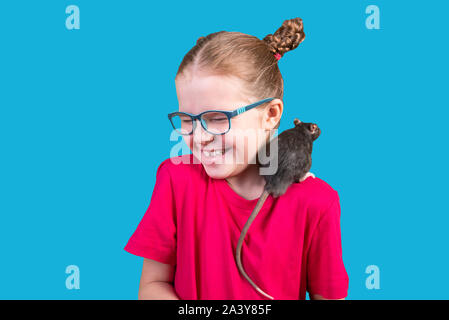 Bambina in bicchieri con un ratto sulla sua spalla. Isolato su uno sfondo blu. Foto Stock