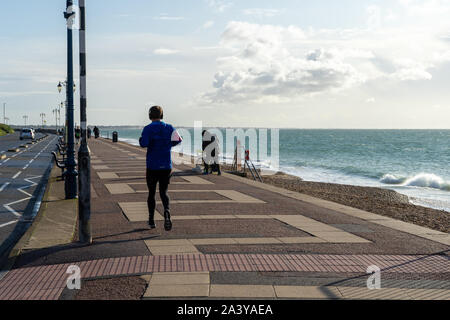 Un giovane uomo correre tutto solo sul lungomare di una spiaggia britannico Foto Stock