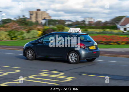 Un istruttori di guida auto in movimento lungo la strada a velocità con lo studente autista guida durante una lezione di guida Foto Stock