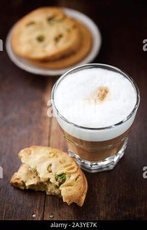 Un bicchiere di latte e caffè pistacchio cookie su sfondo di legno. Immagine simbolica. Close up. Foto Stock