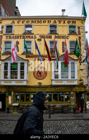 Un giovane che passa su una strada nel centro storico. Tipico pub irlandese e edificio di alloggi sullo sfondo. Dublino, Irlanda. Foto Stock