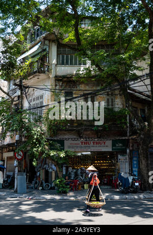 Giovane donna vietnamita che porta cesti di frutta fresca sulla strada del quartiere Vecchio. Hanoi, Vietnam. Foto Stock