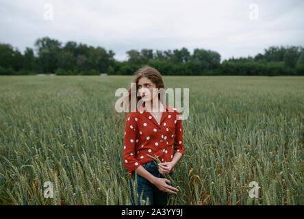 Donna che indossa red polka dot camicia nel campo di grano Foto Stock