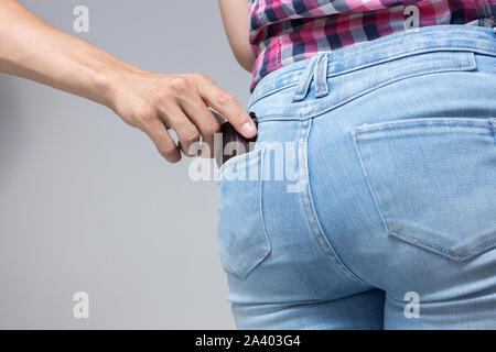 Pickpocketer la mano tirando rubare portafogli al di fuori della tasca posteriore, chiudere fino Foto Stock