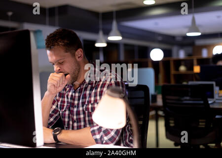 Giovane maschio professionale di lavoro in ritardo in ufficio creativo Foto Stock