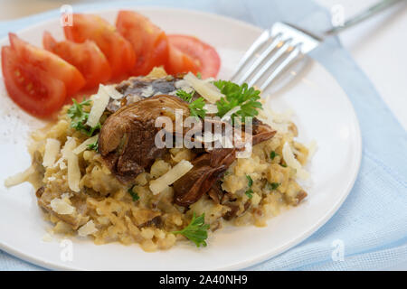 Risotto alla crema di cavolfiore con funghi porcini, vegetariana dieta povera di carboidrati pasto con prezzemolo guarnire il parmigiano e i pomodori su una bianca pl Foto Stock