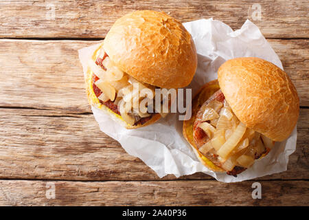 Pan cipolle fritte e costolette di maiale servito su hamburger panini close-up su carta sul tavolo. Parte superiore orizzontale vista da sopra Foto Stock