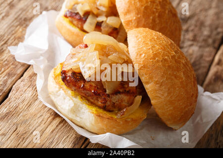 Pan cipolle fritte e costolette di maiale servito su hamburger panini close-up su carta sul tavolo orizzontale. Foto Stock