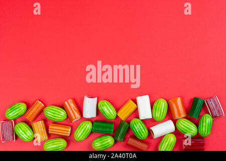 Una fila di caramelle colorate di varie forme su una superficie bianca Foto Stock