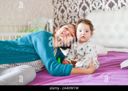 Mom e amore per il bambino sul letto. le emozioni di felicità. kissing baby e avvolgente. Pretty Woman tenendo un neonato nelle sue braccia Foto Stock