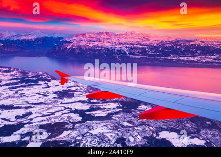 Una vista straordinaria dalla finestra del velivolo durante il tramonto su montagne in Svizzera Foto Stock