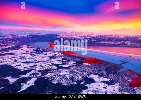 Una vista straordinaria dalla finestra del velivolo durante il tramonto su montagne in Svizzera Foto Stock