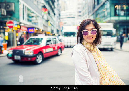 Toothy volto sorridente felicità emozione della donna asiatica permanente sulla hongkong city street Foto Stock
