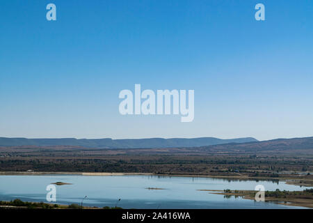 Paesaggio della Crimea. Lago di steppa in primo piano e le montagne coperte di nebbia in background Foto Stock