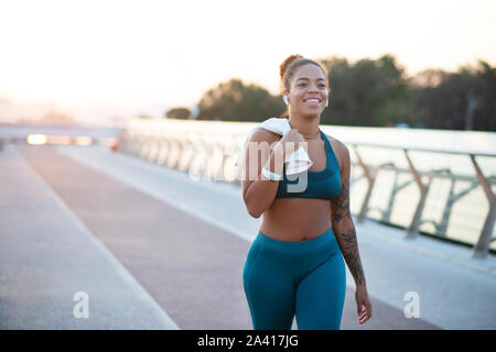 Tatuato giovane donna tornando a casa dopo aver eseguito la mattina Foto Stock