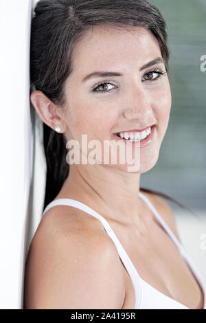 Bella giovane donna appoggiata contro il muro bianco riposo dopo esercizio Foto Stock