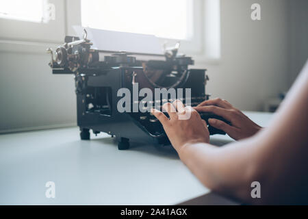 Close up di mani femminili digitando su una macchina da scrivere Foto Stock