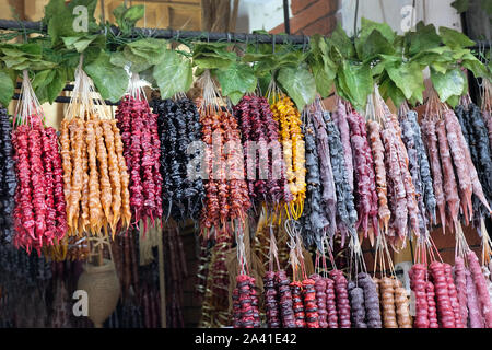 Churchkhela con noci rosso, giallo e marrone e appeso a un filo sul contatore. Dolci tradizionali in Georgia. Delizioso e sano desse georgiano Foto Stock