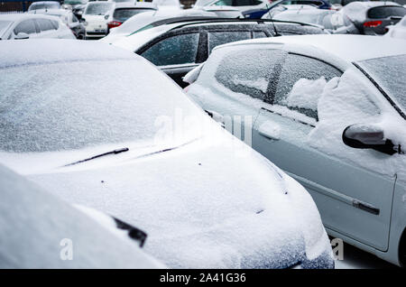 Parcheggiate le auto nel parcheggio dopo la tempesta di neve Foto Stock
