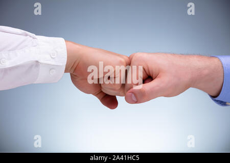 Close-up di due uomini di affari dando Fist Bump per il successo del lavoro di squadra contro lo sfondo grigio Foto Stock