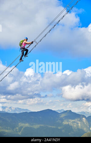 Donna sulla via ferrata Donnerkogel Intersport Klettersteig nelle Alpi austriache, vicino Gosau. Scala verso il cielo del concetto. Foto Stock