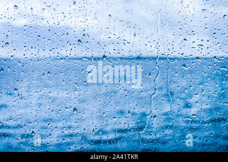 Gocce d'acqua sul vetro su sfondo blu Foto Stock